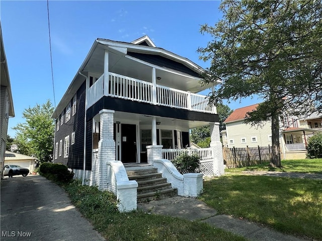 american foursquare style home with a porch, a front yard, and a balcony