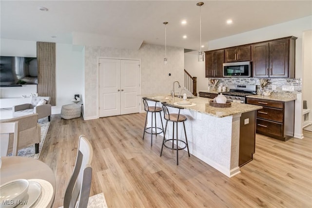 850-4 Dipper Ln, Aurora, OH 44202 - kitchen featuring dark brown cabinetry, appliances with stainless steel finishes, a kitchen island with sink, a sink, and light wood finished floors
