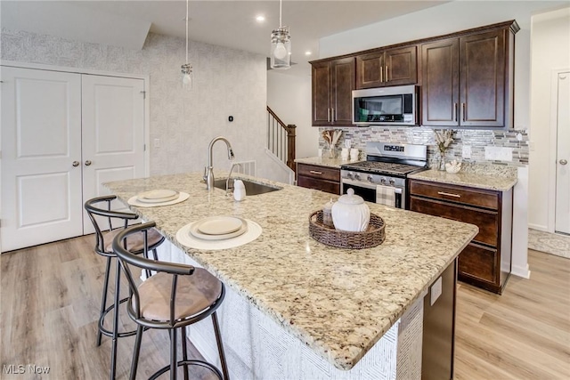850-4 Dipper Ln, Aurora, OH 44202 - kitchen featuring light wood-type flooring, appliances with stainless steel finishes, a sink, and a center island with sink