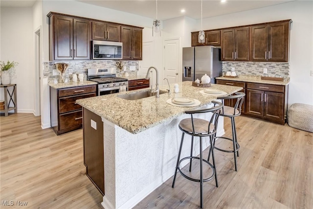 850-4 Dipper Ln, Aurora, OH 44202 - kitchen with a sink, light wood-type flooring, dark brown cabinetry, stainless steel appliances, and decorative backsplash