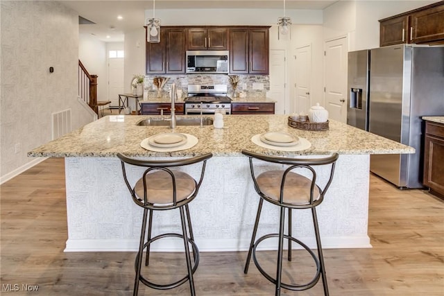 850-4 Dipper Ln, Aurora, OH 44202 - kitchen with baseboards, a kitchen island with sink, light wood-style floors, stainless steel appliances, and a sink