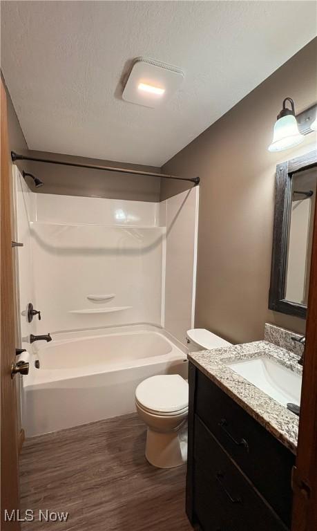 bathroom with toilet, shower / bath combination, wood finished floors, and vanity