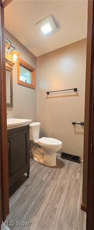 bathroom featuring vanity, visible vents, toilet, and wood finished floors