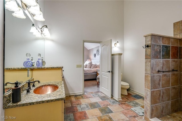 full bath with tiled shower, vanity, ensuite bath, stone finish flooring, and toilet