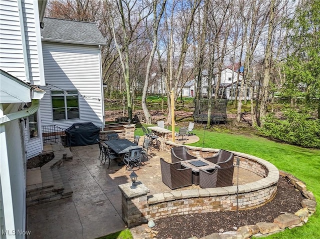 view of patio featuring an outdoor fire pit, a grill, and a trampoline