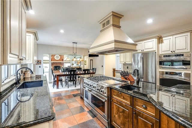kitchen featuring a sink, backsplash, appliances with stainless steel finishes, and custom range hood