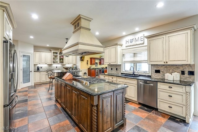 kitchen featuring cream cabinets, a kitchen island, a sink, stainless steel appliances, and decorative backsplash