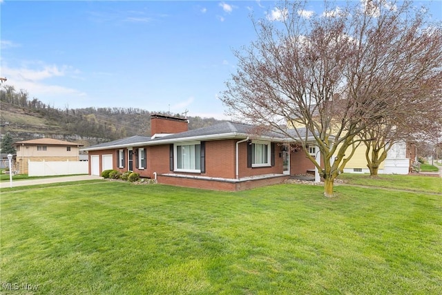 ranch-style house featuring a chimney, driveway, a front yard, brick siding, and a garage