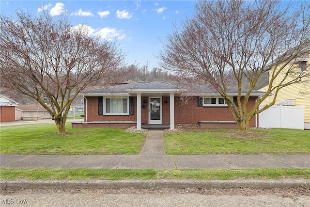 view of front of house with brick siding, a front yard, and fence