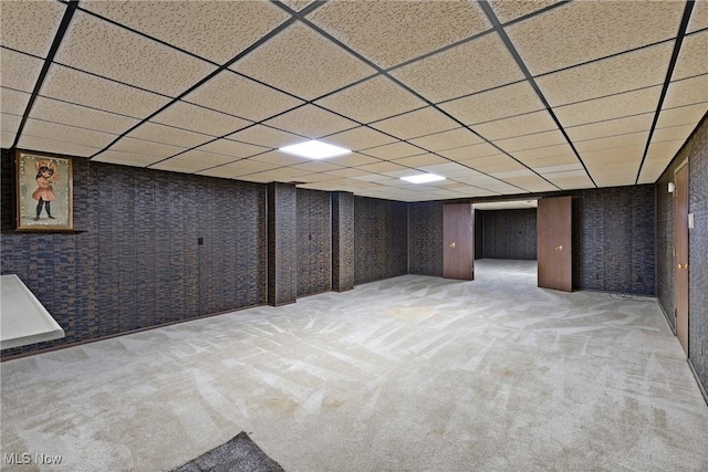 finished below grade area featuring a paneled ceiling and carpet