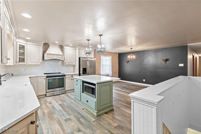 kitchen featuring light countertops, premium range hood, light wood-style floors, stainless steel appliances, and a sink