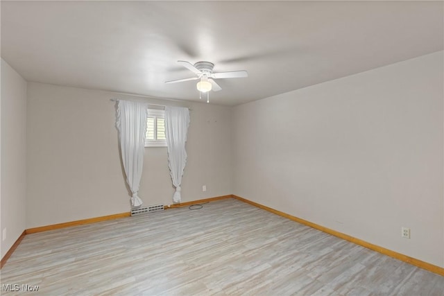 spare room featuring light wood finished floors, baseboards, and a ceiling fan