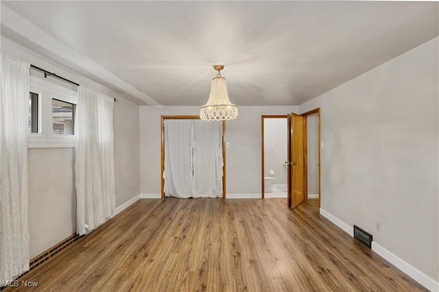 unfurnished dining area with visible vents, baseboards, an inviting chandelier, and wood finished floors