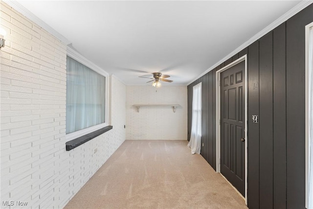 corridor with ornamental molding, carpet floors, and brick wall