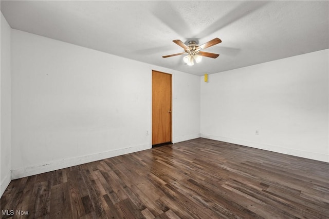 unfurnished room with dark wood-type flooring, baseboards, and a ceiling fan