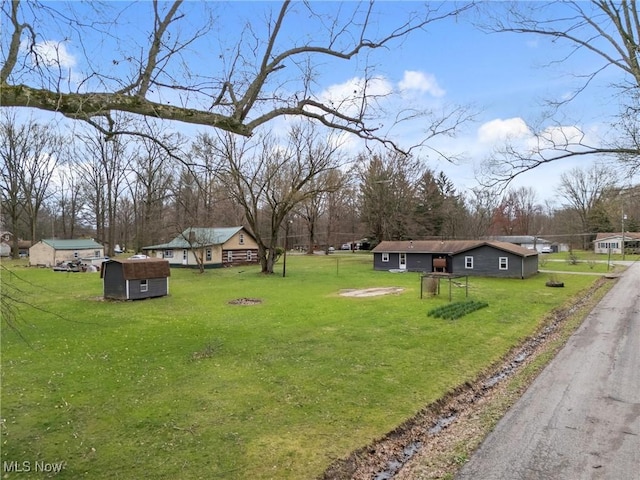 view of yard with a storage unit, driveway, and an outdoor structure
