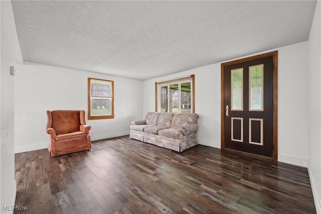 living area featuring dark wood-type flooring, a textured ceiling, and baseboards