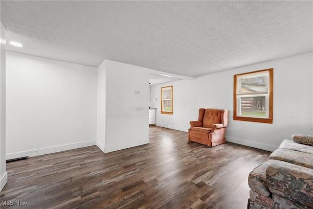 living room featuring a textured ceiling, wood finished floors, and baseboards