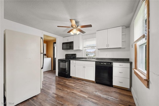 kitchen featuring open shelves, dark countertops, white cabinets, black appliances, and a sink