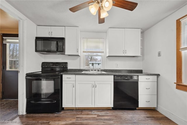 kitchen featuring white cabinetry, dark countertops, black appliances, ceiling fan, and a sink