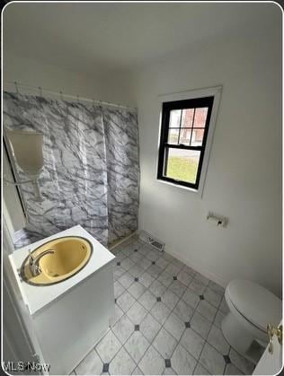 bathroom with toilet, a sink, and tile patterned flooring
