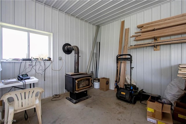 misc room featuring unfinished concrete flooring and a wood stove