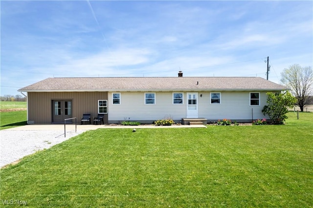 back of property featuring a lawn and a shingled roof