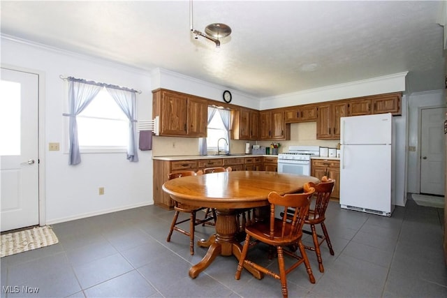 dining room with dark tile patterned flooring, crown molding, and baseboards