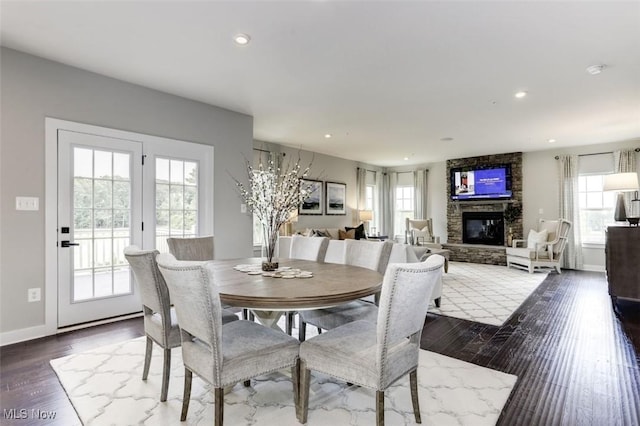 dining space with a healthy amount of sunlight, a fireplace, dark wood-style floors, and baseboards