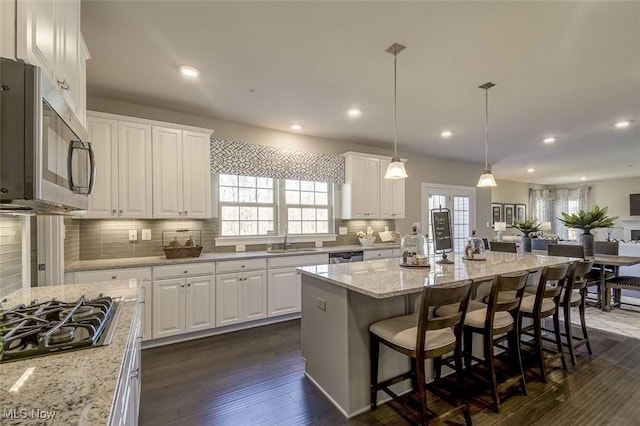 kitchen featuring stainless steel appliances, a wealth of natural light, white cabinets, and a sink
