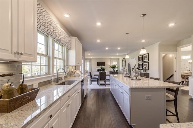 kitchen featuring a sink, open floor plan, white cabinets, and recessed lighting