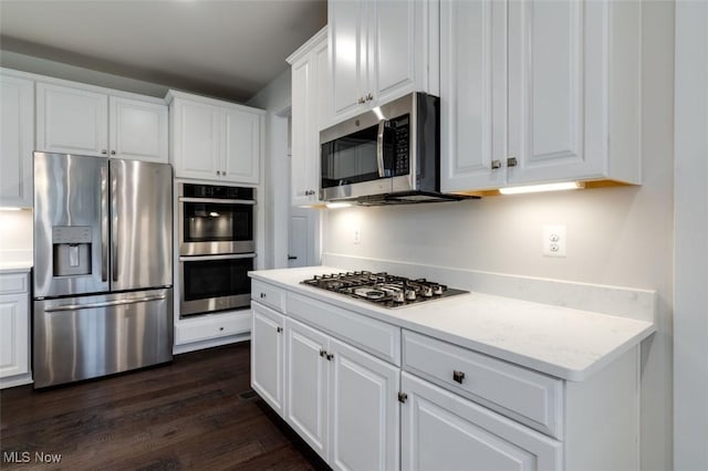 kitchen featuring dark wood-type flooring, light countertops, white cabinets, and stainless steel appliances