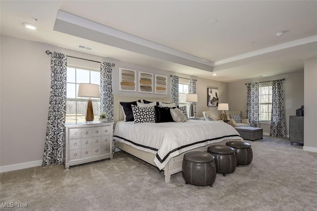 carpeted bedroom with visible vents, baseboards, multiple windows, and a tray ceiling