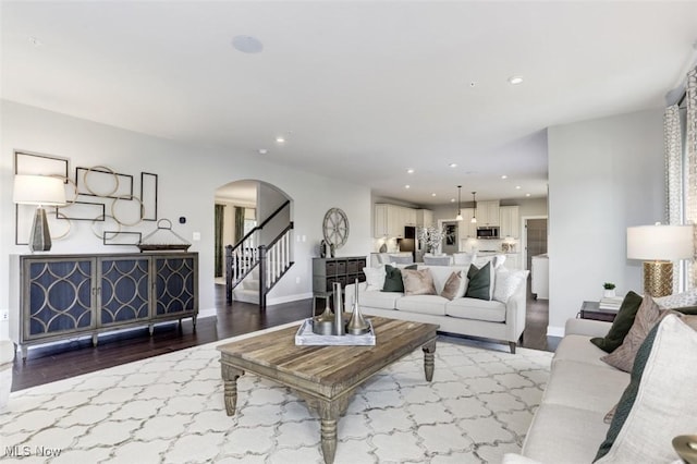 living area featuring arched walkways, recessed lighting, stairway, wood finished floors, and baseboards