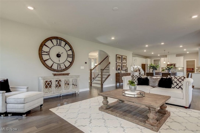 living room featuring recessed lighting, arched walkways, and dark wood finished floors