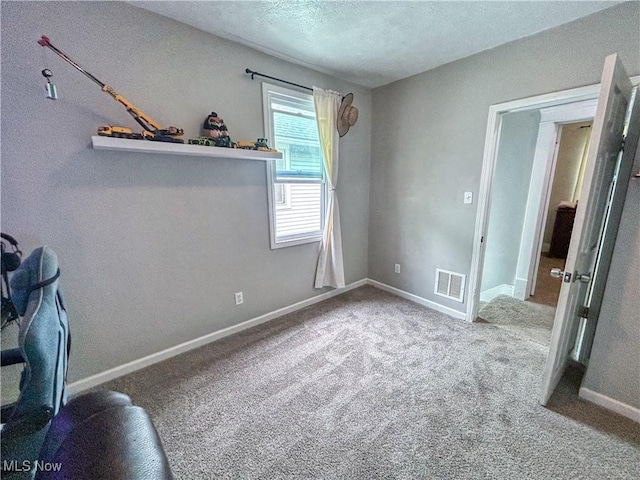 unfurnished bedroom with a textured ceiling, baseboards, visible vents, and carpet floors