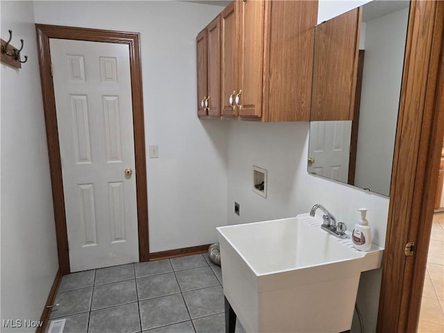 laundry area featuring baseboards, tile patterned floors, washer hookup, cabinet space, and a sink