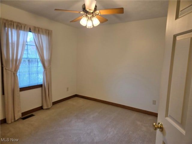 spare room with visible vents, light colored carpet, baseboards, and ceiling fan
