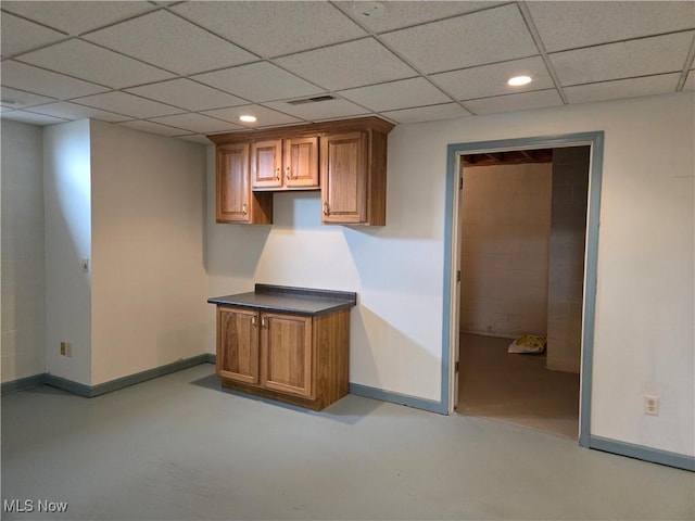 interior space with recessed lighting, concrete floors, a drop ceiling, and baseboards
