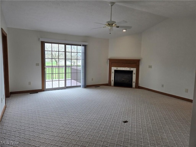 unfurnished living room with a tiled fireplace, ceiling fan, carpet flooring, and baseboards