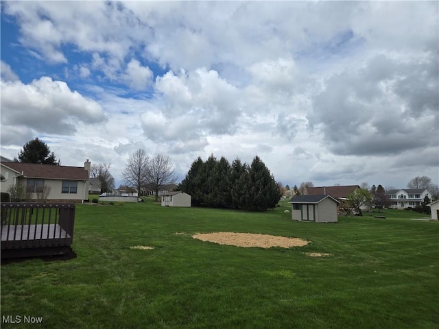 view of yard with an outbuilding, a deck, and a shed