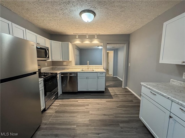 1313 12th St, Vienna, WV 26105 - kitchen with track lighting, a textured ceiling, a sink, stainless steel appliances, and dark wood-style floors