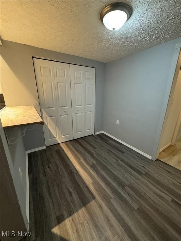 1313 12th St, Vienna, WV 26105 - unfurnished bedroom featuring dark wood-style flooring, a closet, baseboards, and a textured ceiling