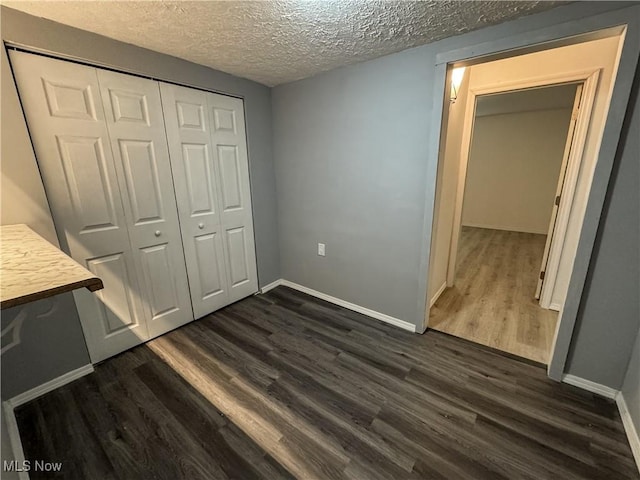 1313 12th St, Vienna, WV 26105 - unfurnished bedroom featuring dark wood-type flooring, a closet, baseboards, and a textured ceiling