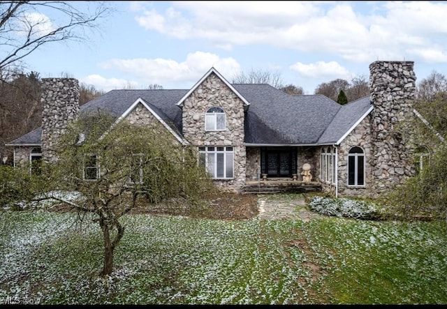 view of front facade with french doors, a chimney, a shingled roof, and stone siding