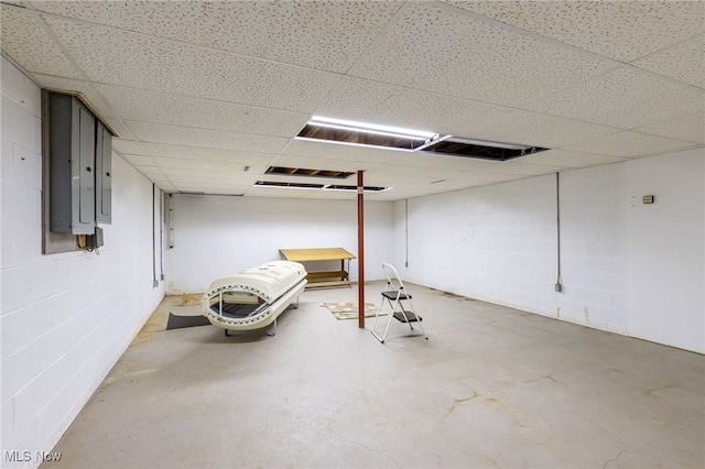 finished basement with a drop ceiling and concrete block wall