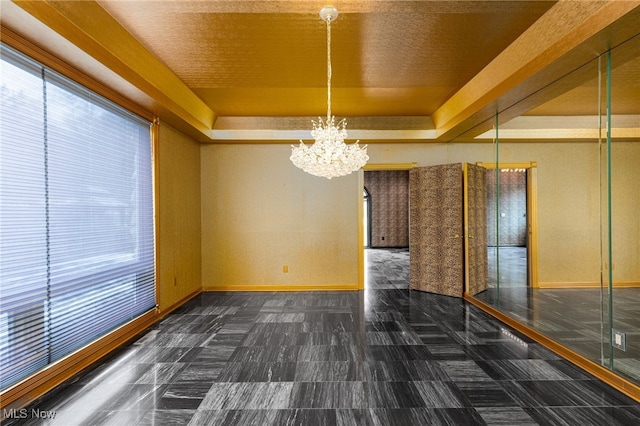 unfurnished dining area featuring a tray ceiling, baseboards, and an inviting chandelier
