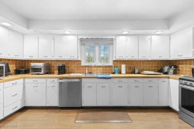 841 W Milton St, Alliance, OH 44601 - kitchen with light wood-style flooring, appliances with stainless steel finishes, a sink, light countertops, and backsplash