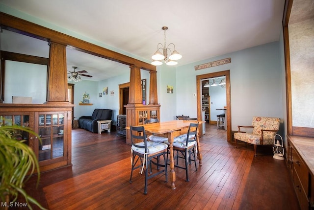 144 S Walnut St, Gnadenhutten, OH 44629 - dining space featuring decorative columns, dark wood-style flooring, and ceiling fan with notable chandelier