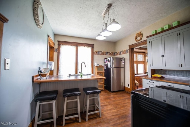 144 S Walnut St, Gnadenhutten, OH 44629 - kitchen featuring a sink, freestanding refrigerator, black range with electric cooktop, a healthy amount of sunlight, and a textured ceiling
